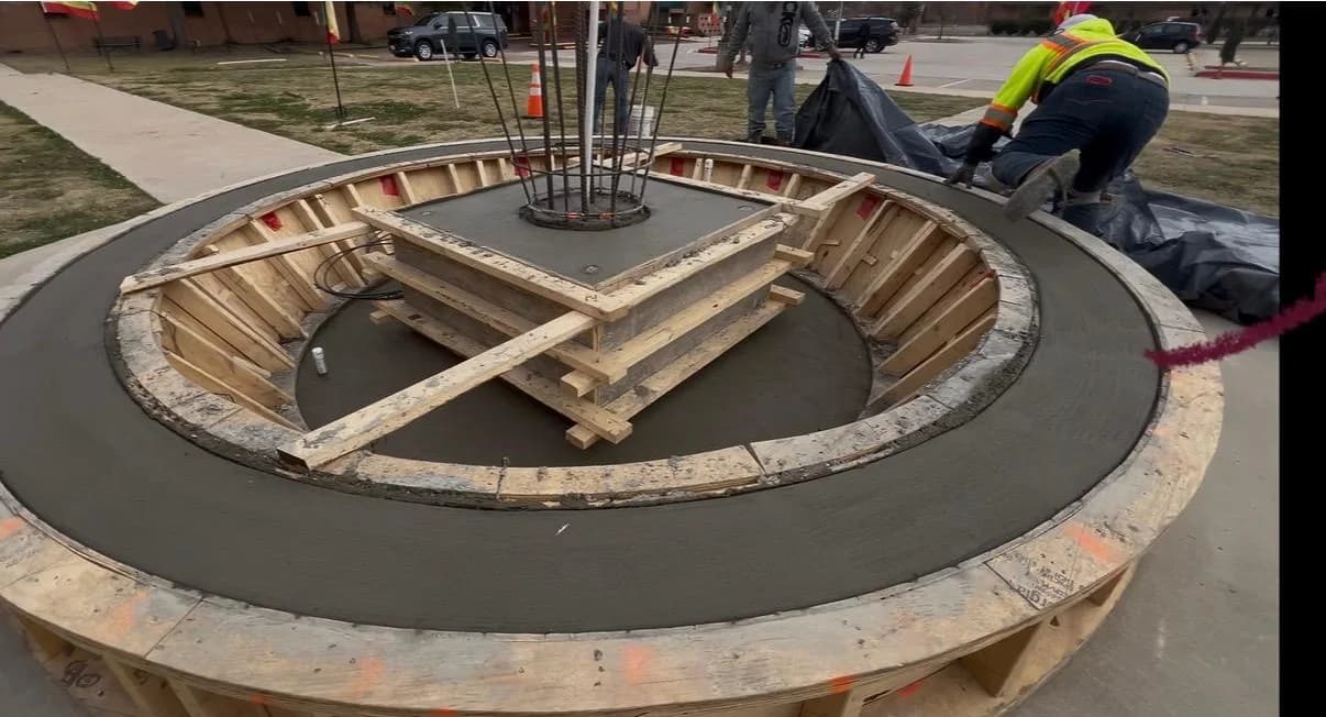 Crew placing and finishing concrete in circular formwork for a monument base