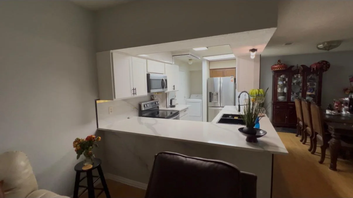 The opened kitchen looking through from the dining room across the quartz peninsula